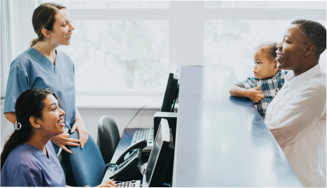 two nurses at a front desk talking to a patient and her child